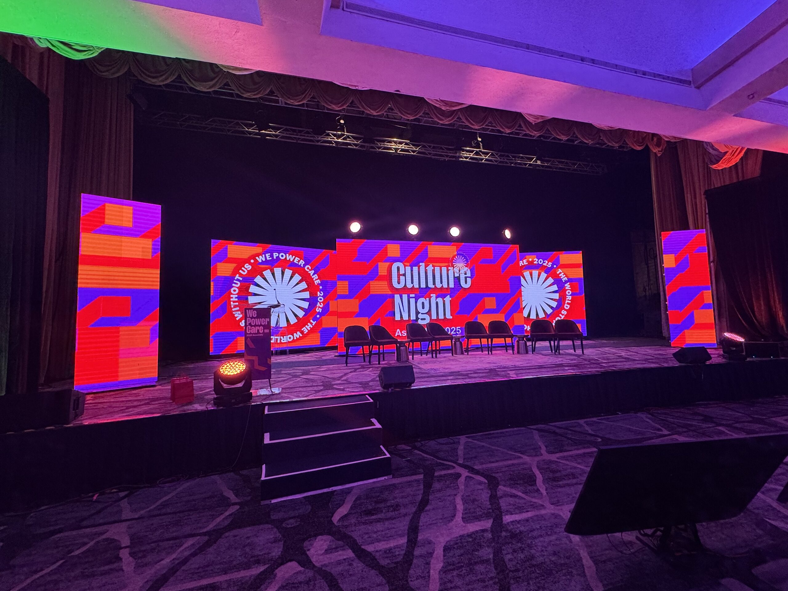 Colorful stage setup for "Culture Night" event, featuring illuminated screens, chairs, and a podium. Designed to showcase cultural presentations.